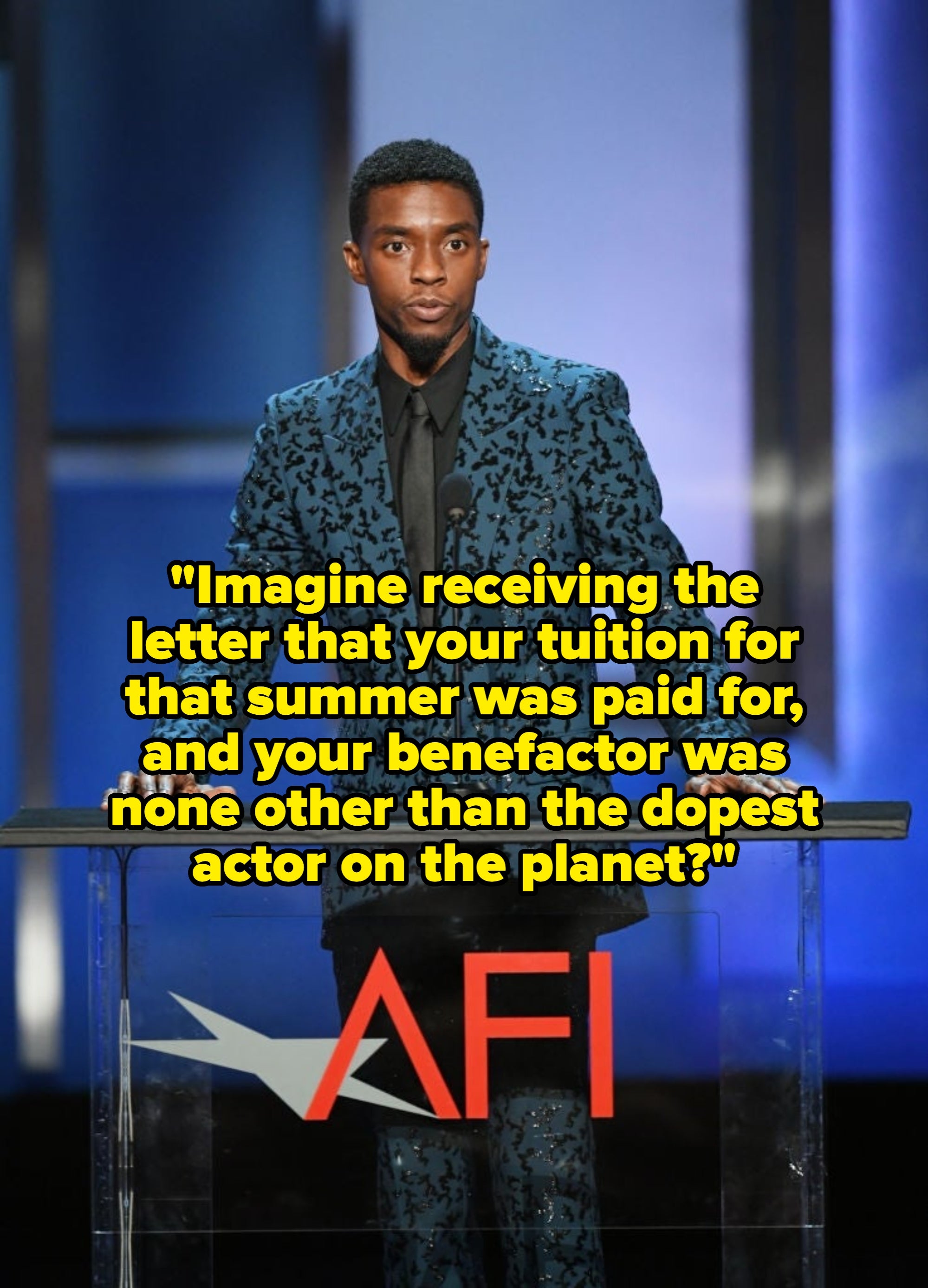 A person in a patterned suit speaks at a podium with "AFI" on it, standing in a formal setting