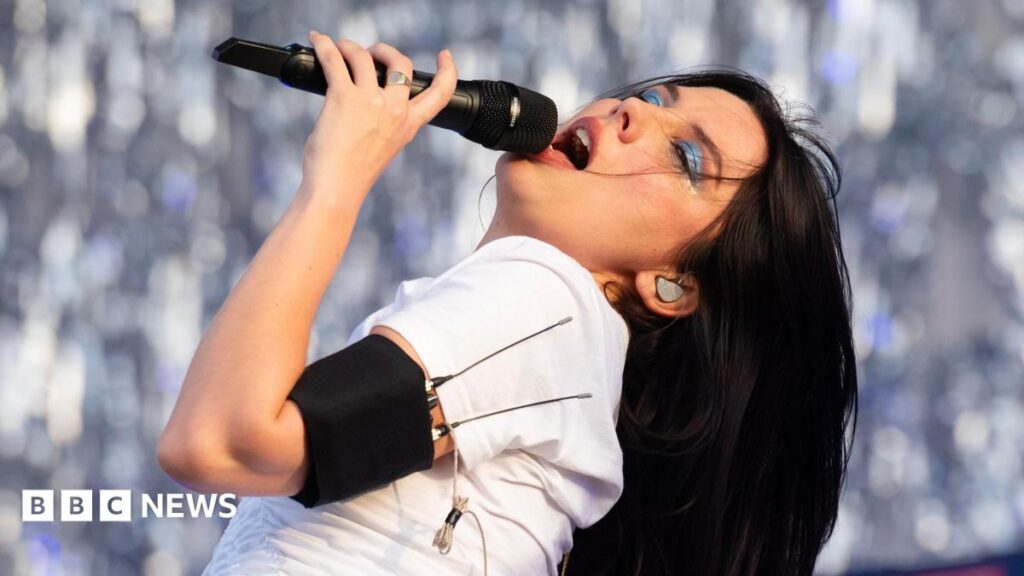 Ellie Rowsell of Wolf Alice closes her eyes and throws her head back as she sings into a microphone during the band's headline set at Finsbury Park