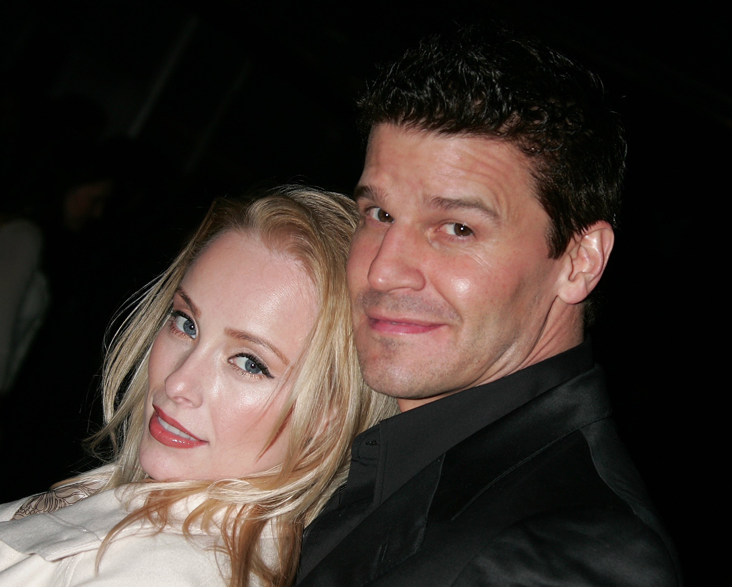 Jamie Bergman smiles while posing with her husband, David Boreanaz, who wears a black jacket