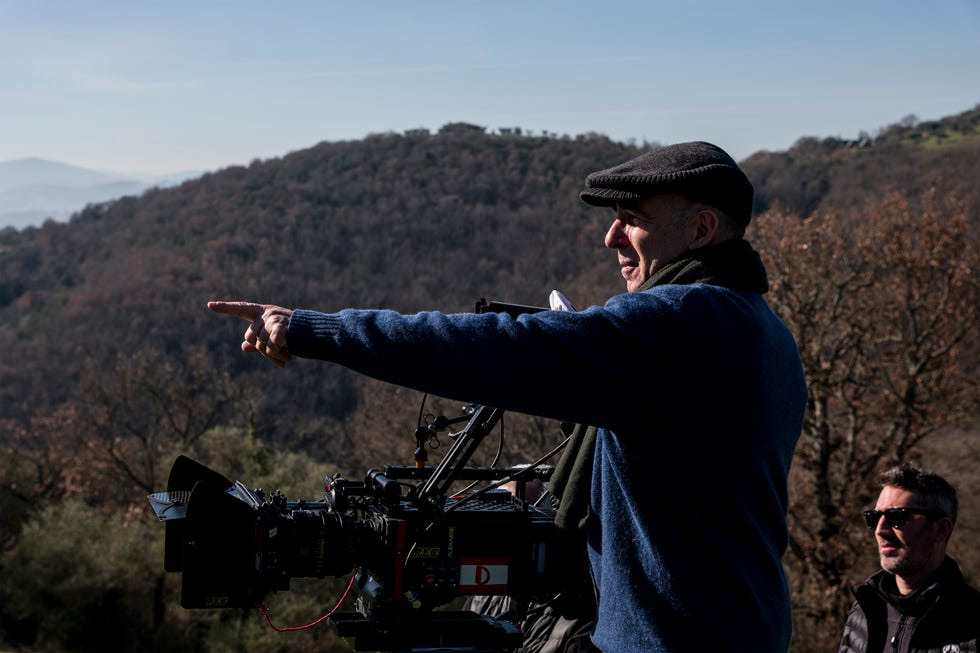 A director gestures while overseeing a filming scene in a mountainous landscape. A director gestures while overseeing a filming scene in a mountainous landscape.
