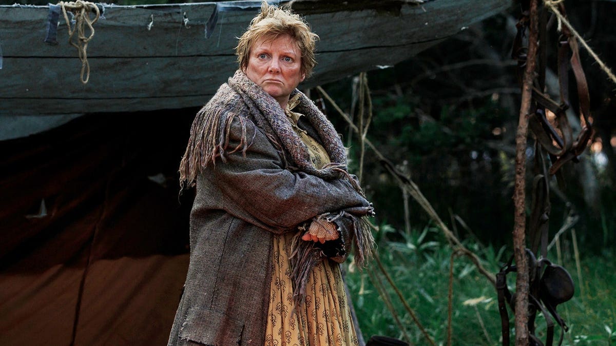 Alison Arngrim stands in costume on a set.