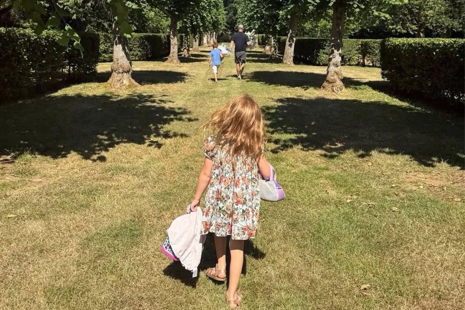 Princess Lilibet carries flowers as she walks behind Prince Harry and Prince Archie on the Althorp Estate, near Princess Diana's grave. The image was posted to Instagram by Meghan Markle on July 24.