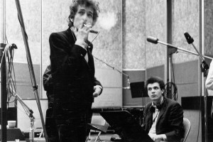 NEW YORK - SUMMER 1965: Bob Dylan (holding a cigarette) and guitarist Mike Bloomfield (seated) take a break during the recording of the album 'Highway 61 Revisited' surrounded by an assortment of microphones, amplifiers and guitars in Columbia's Studio A in the summer of 1965 in New York City, New York. (Photo by Michael Ochs Archives/Getty Images)