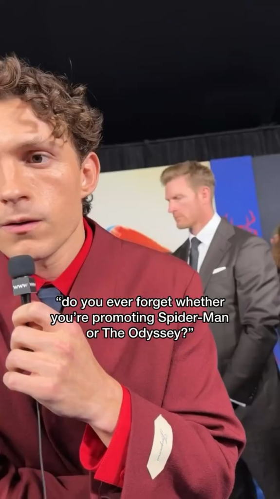 Tom Holland looks down to see what he’s wearing to find out if he’s either promoting ‘Spider-Man: Brand New Day’ or ‘The Odyssey’