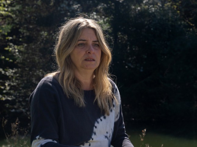 An emotionally-broken Charity Dingle sitting at the edge of a lake in Emmerdale.