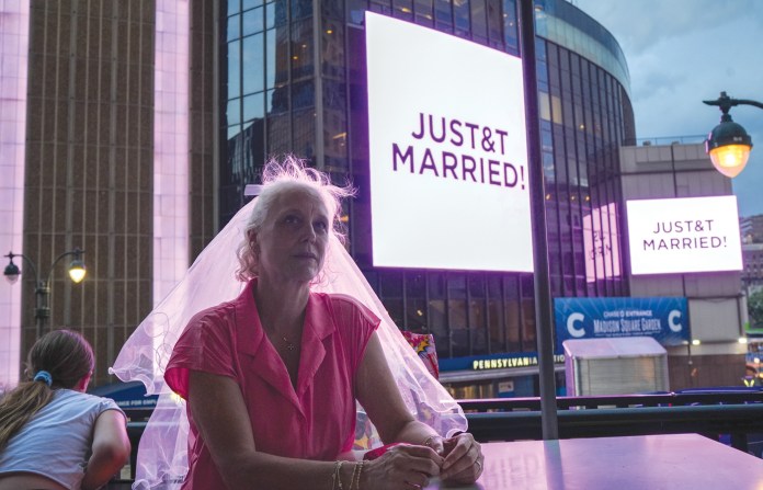 A Taylor Swift fan sits at a restaurant next to Madison Square Garden where a “JUST&T MARRIED” sign is displayed following the wedding of Taylor Swift and Travis Kelce on July 3 in New York. (Ryan Murphy/AP)