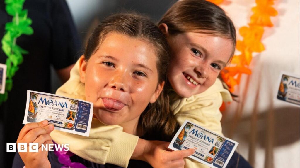 A close-up image of two girls holding 'Moana Exclusive Screening' cinema tickets.  One is poking her tongue out. They are both smiling and looking into the camera.