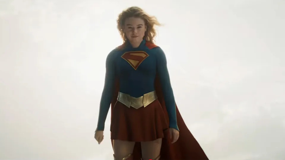 A look at Kara's blue and red suit in the Supergirl movie. She's in the air embracing a yellow sun.