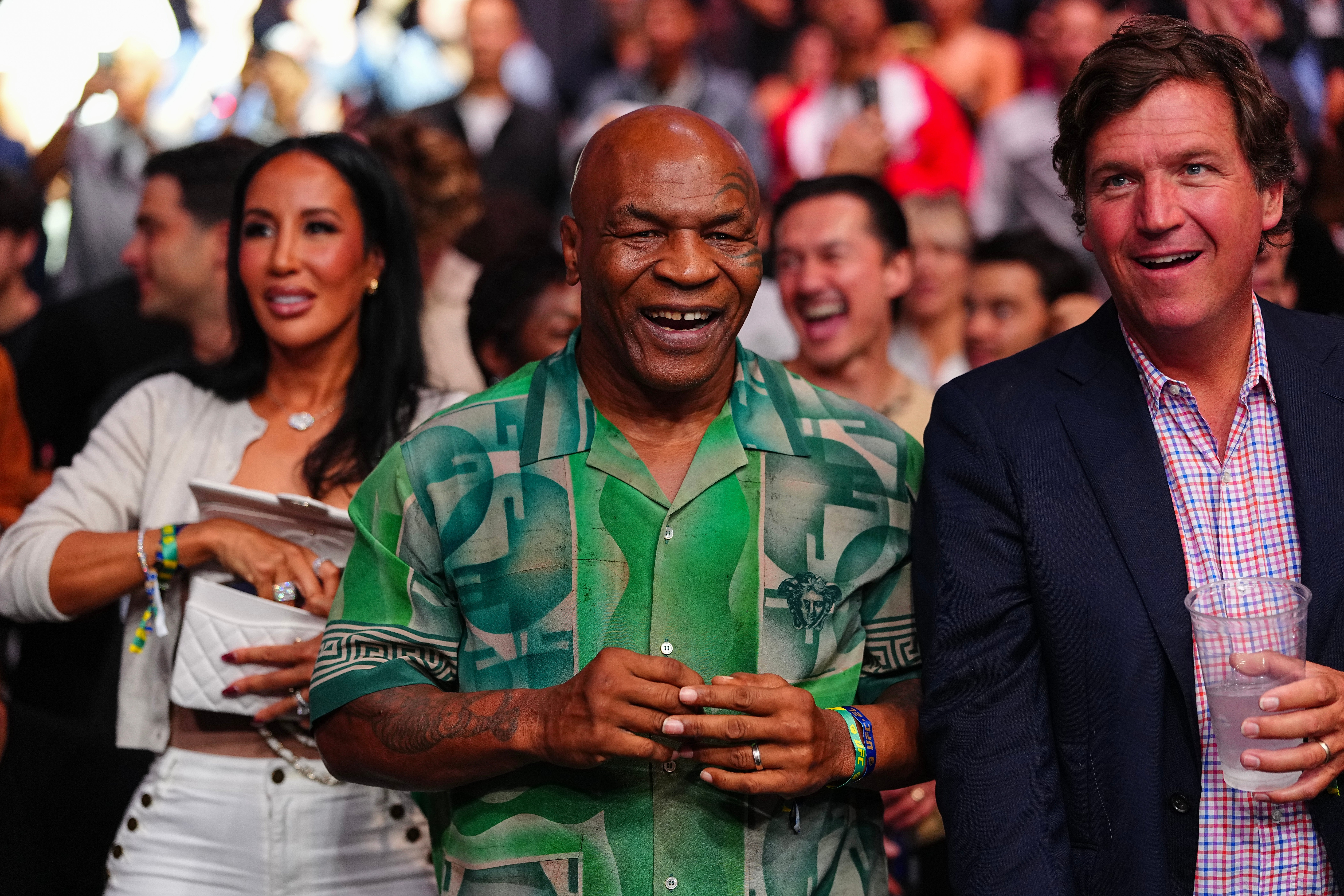 Mike Tyson and Tucker Carlson smile at a UFC fight