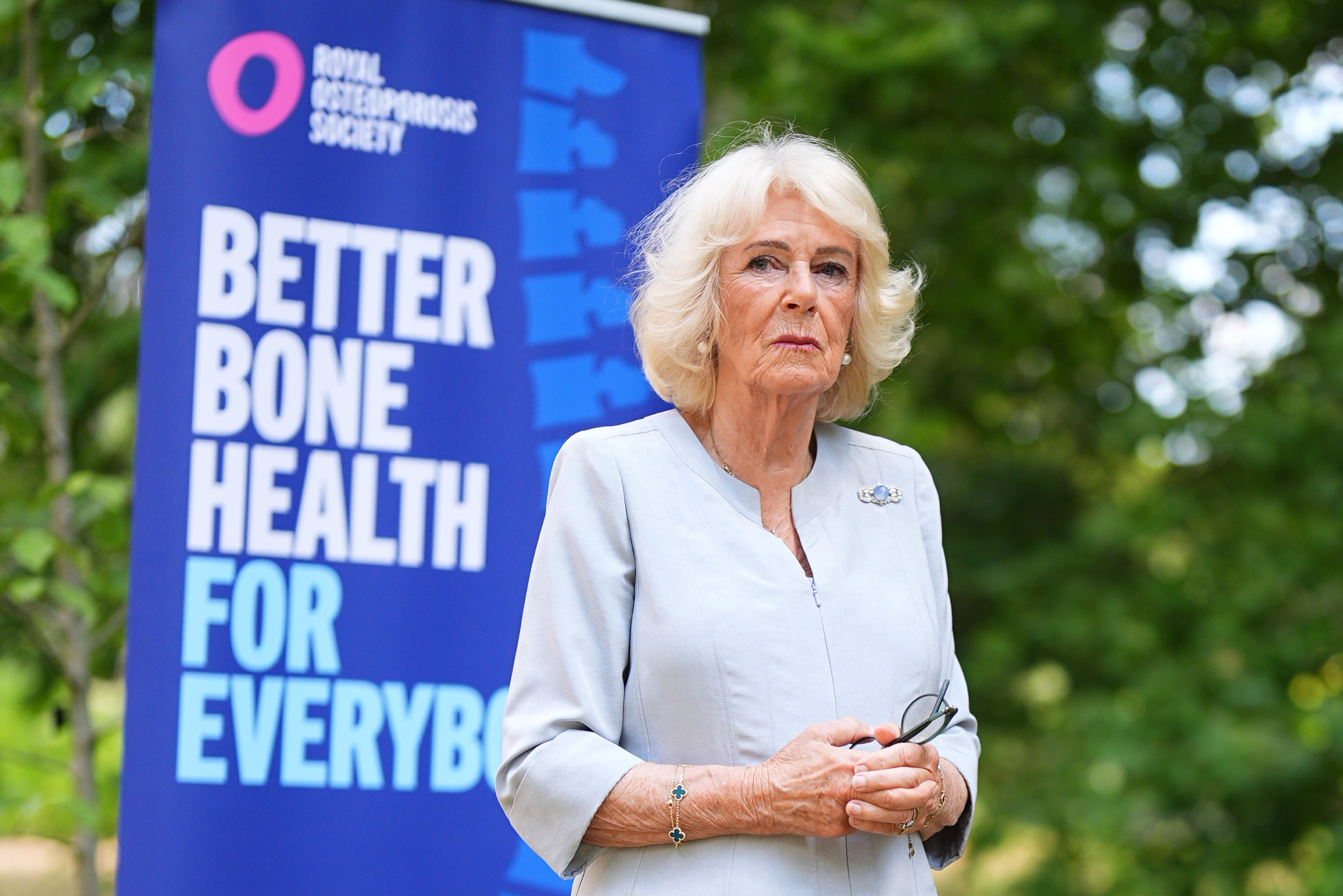 Queen Camilla standing in front of a bone health poster
