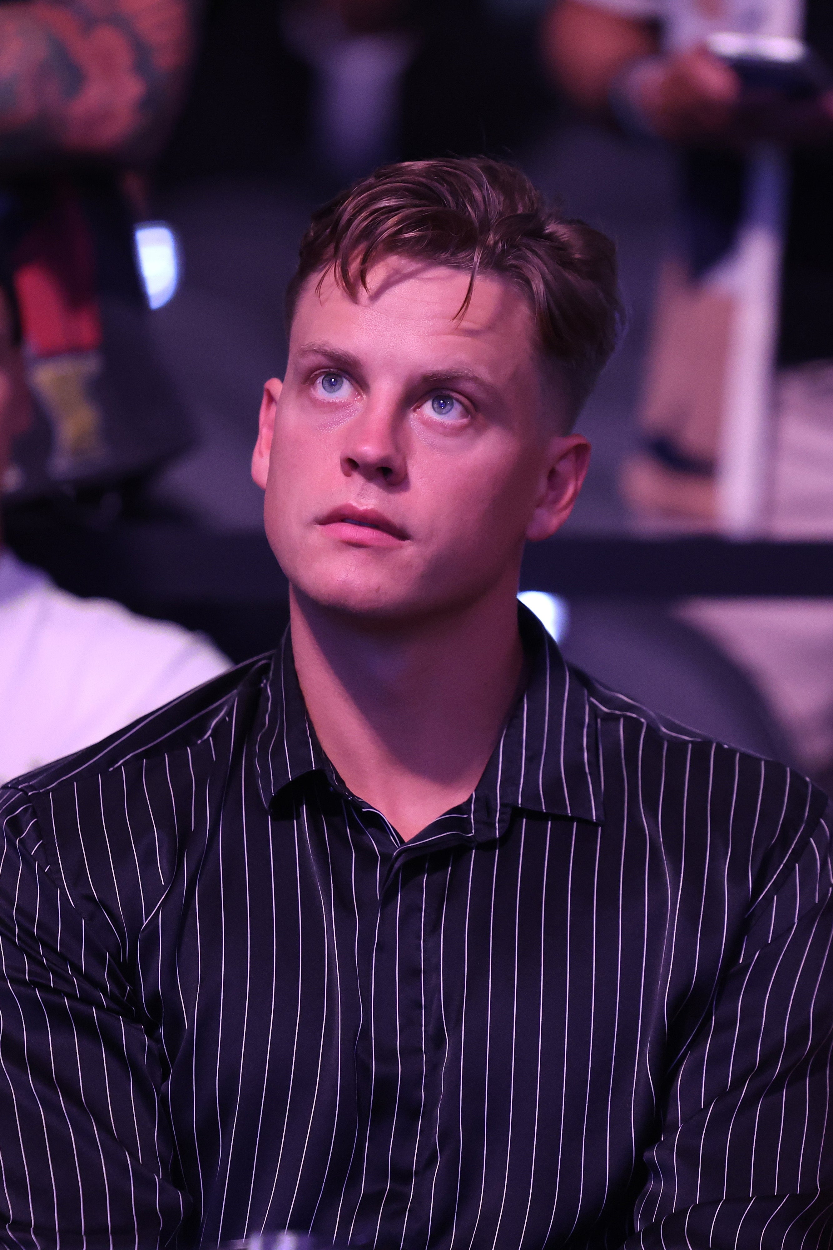 Joe Burrow in a striped shirt looking upwards at a UFC fight