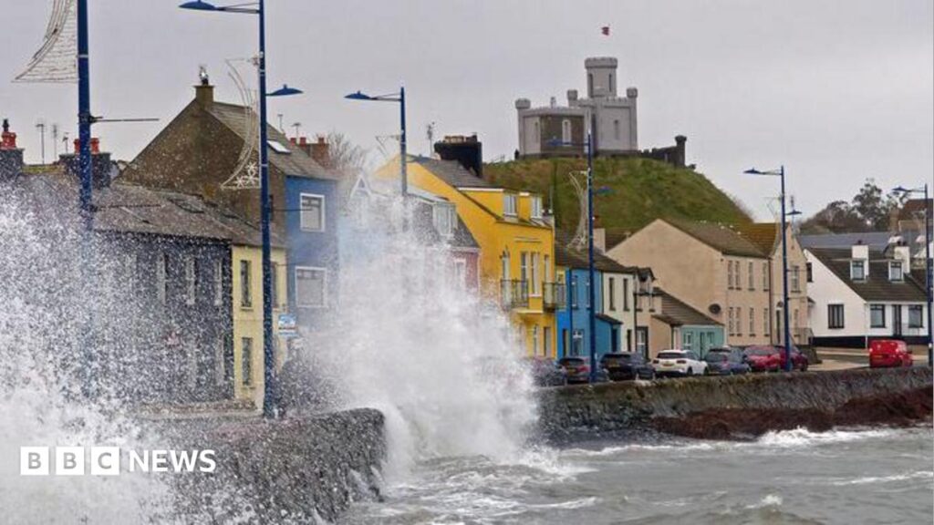 Hope Street: How a TV show has drawn Australians and Americans to Donaghadee An image of the seafront at Donaghadee, colourful houses can be seen along the promenade while waves break against the sea wall and spray up onto the road. It is an overcast day.