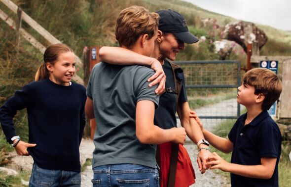Princess Catherine drapes an arm around Prince George as Prince Louis takes her hand and Princess Charlotte looks on
