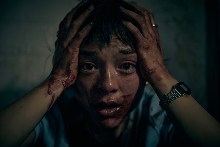 Production image: Hana's face is covered in blood.