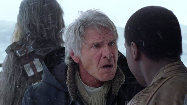 Harrison Ford as Han Solo hollers in the snow at John Boyega as Finn in Star Wars: The Force Awakens
