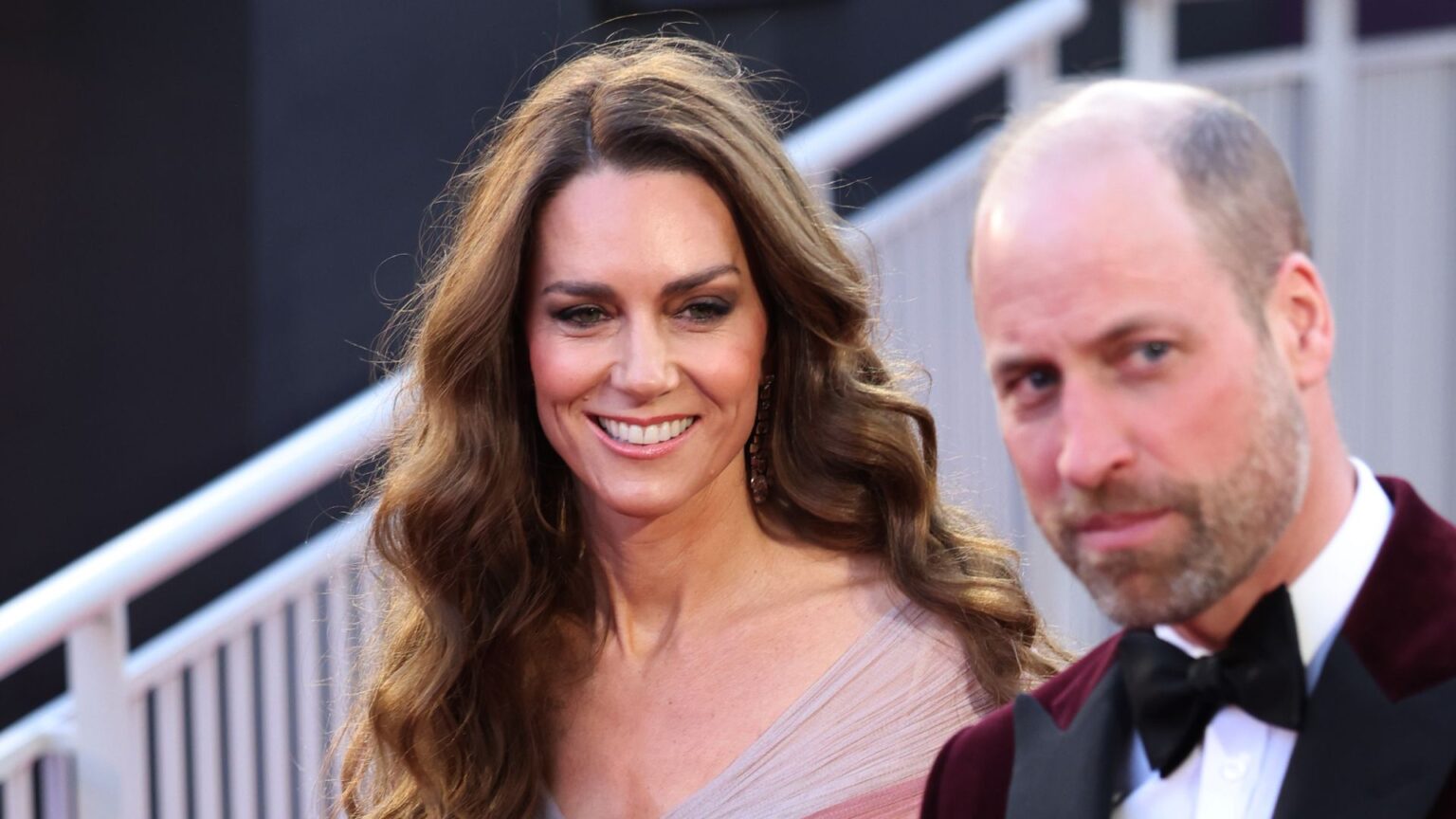 Princess Kate and Prince William Are Entering a New Chapter Princess Kate wears a pink gown to attend the BAFTAs 2026 with husband Prince William who has a bald head, a beard, and is wearing a burgundy velvet jacket