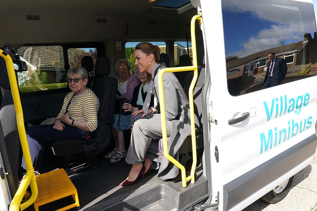 Several people sit inside a minibus with its side door open.